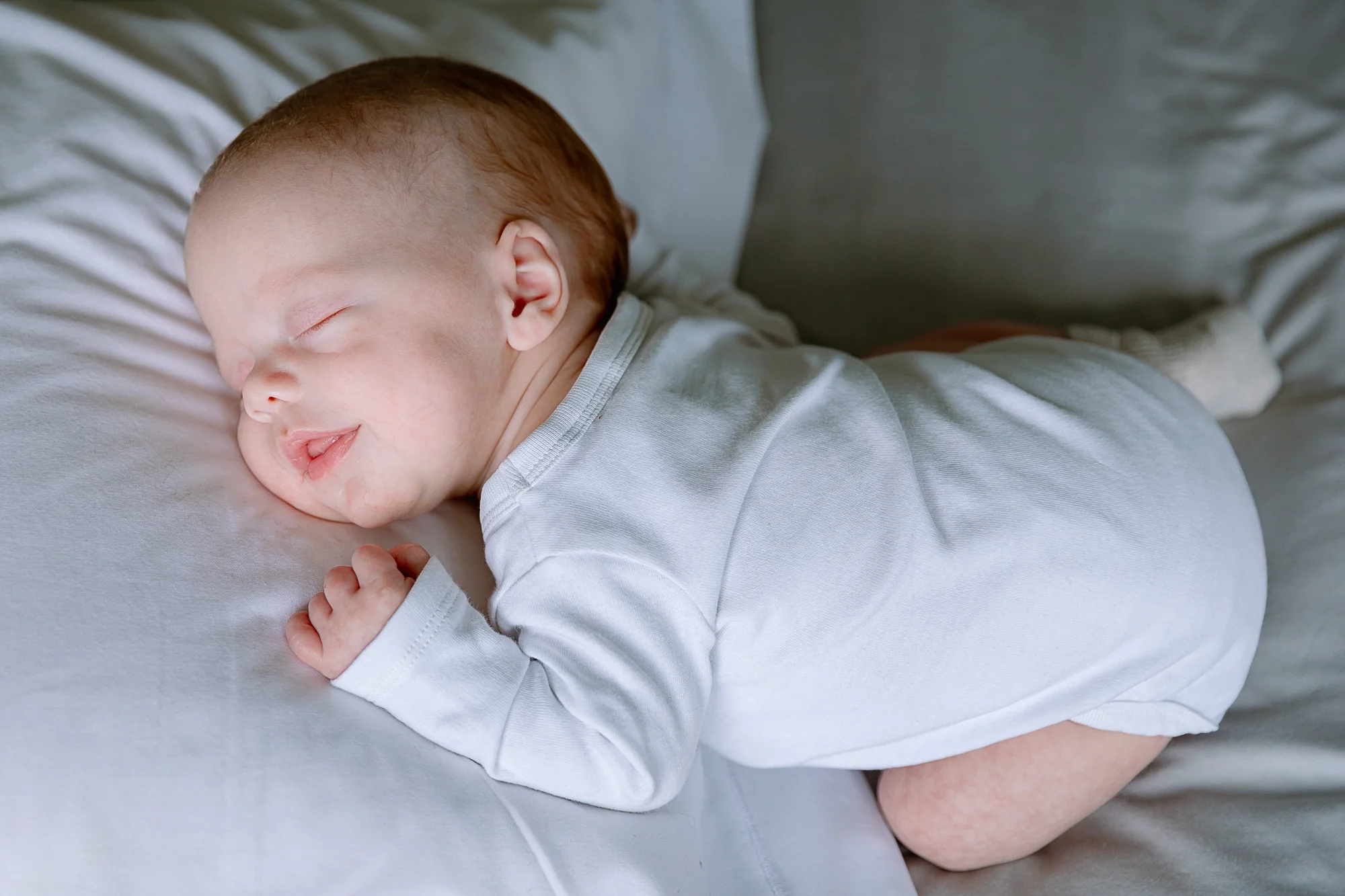 Pure rustige babyfoto van baby in wit rompertje.