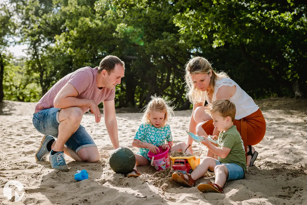 Jong gezin spelen met zand tijdens een ongedwongen fotoshoot in Brabant.