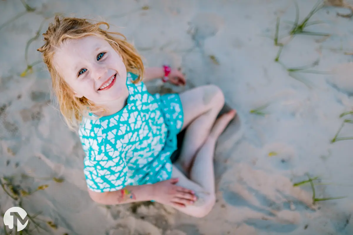 Meisje zitten in het zand van bovenaf gefotografeerd.