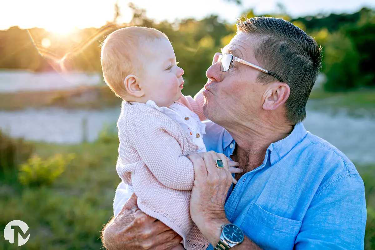 Opa en kleindochter geven elkaar een kusje tijdens een familie fotoshoot.