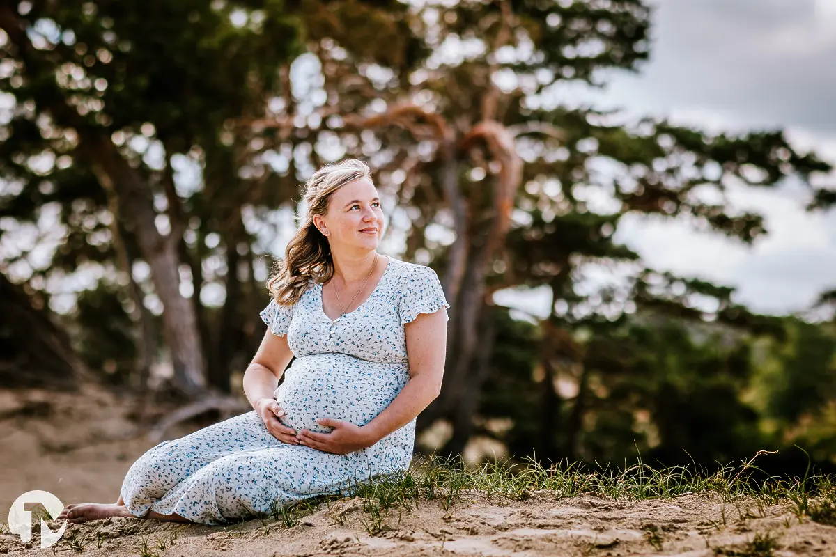 Zwangerevrouw tijdens een ontspannen fotoshoot in de natuur.