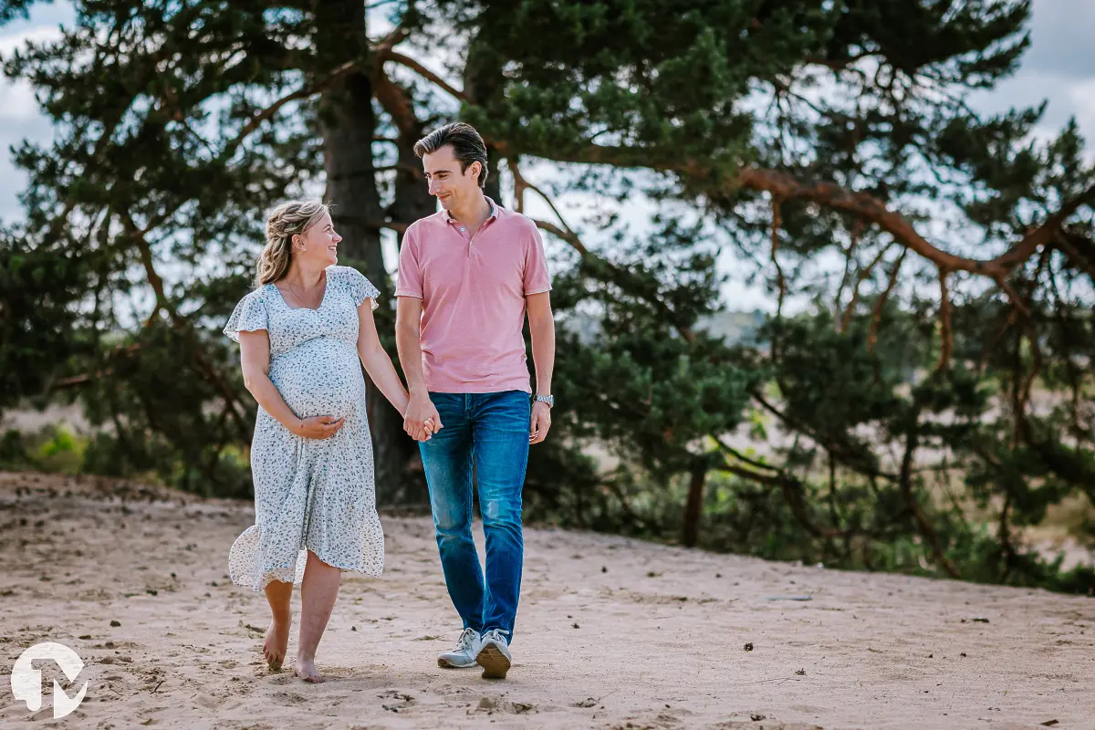 Zwangere vrouw loopt samen met haar man door de Loonse duinen in Brabant.