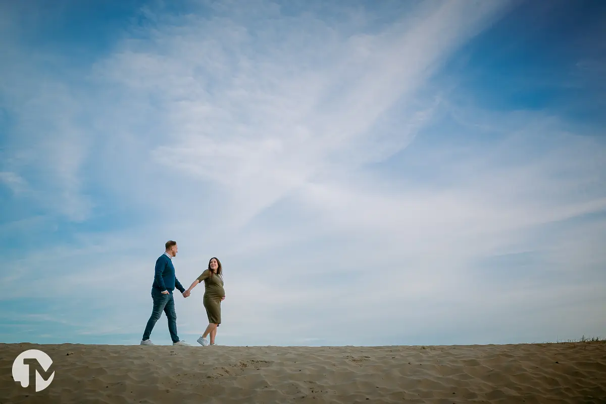 Man en zwangere vrouw kussen elkaar voor groene bebossing.