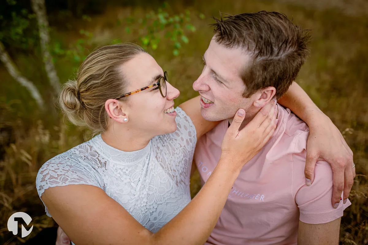 Verliefd stel kussen elkaar tijdens een loveshoot terwijl ze in het gras zitten