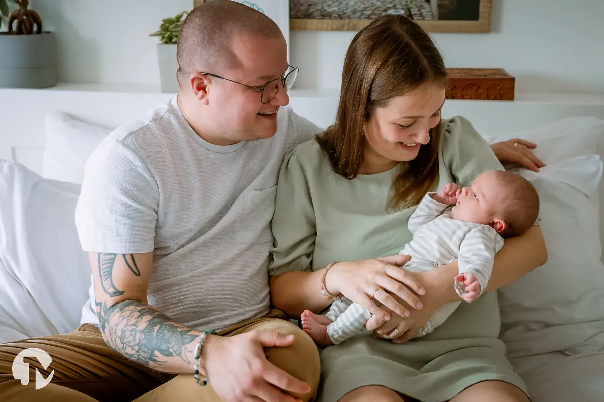 Jong gezin geniet van hun baby op bed tijdens een niet geposeerde baby fotoshoot in Tilburg.