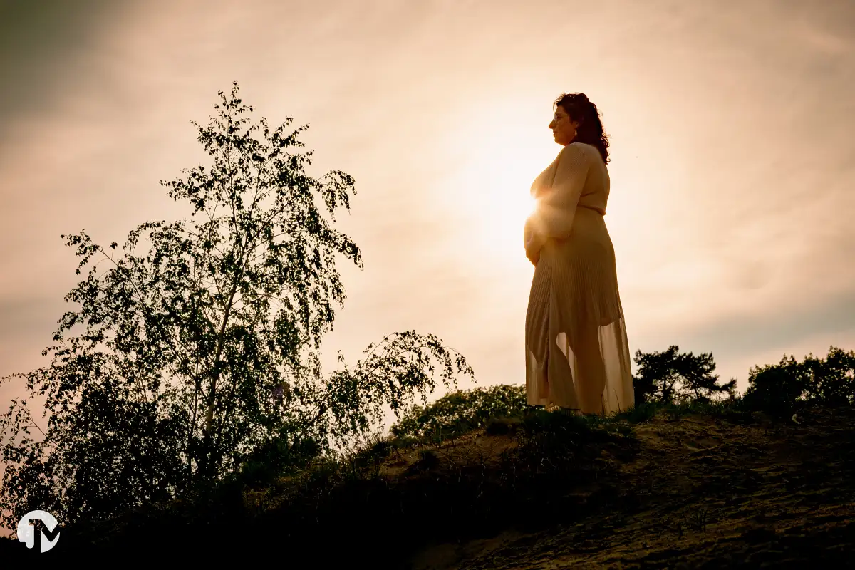 Silhouette van zwangere vrouw bij ondergaande zon.