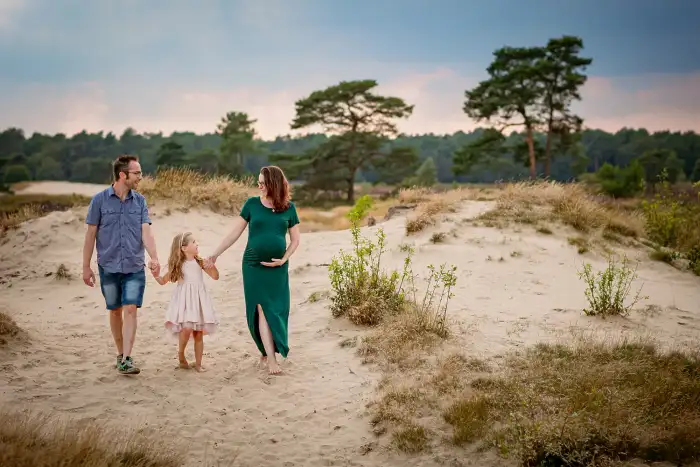 Jong gezin loopt in de avondzon door de Loonse Duinen.