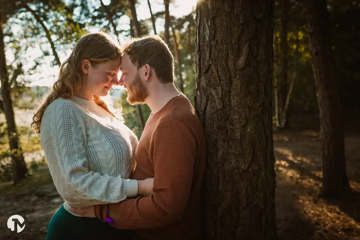 Loveshoot bij zonsondergang, verliefd stel met hoofden tegen elkaar met de warme zon op de achtergrond.