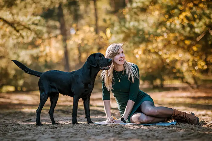 Vrouw met hond in natuurlijke pose tijdens een huisdieren fotoshoot in bosrijke omgeving Katjeskelder Oosterhout