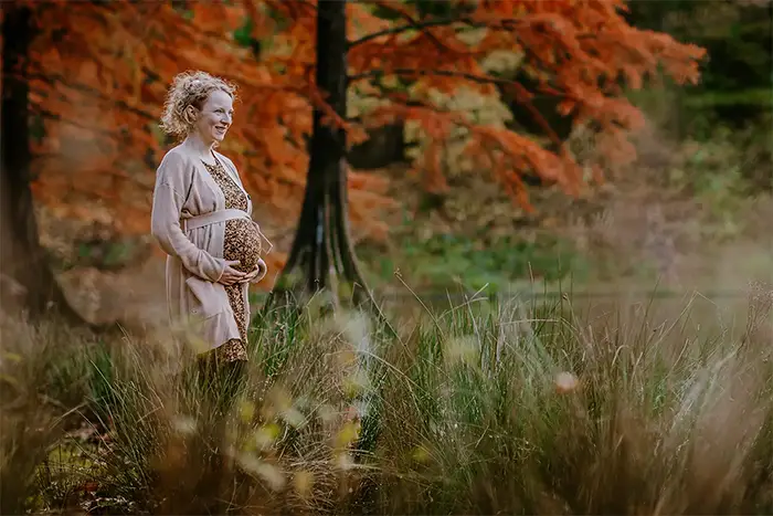Kleurrijke zwangerschapsshoot in de natuur in de herfst door een fijne portretfotograaf