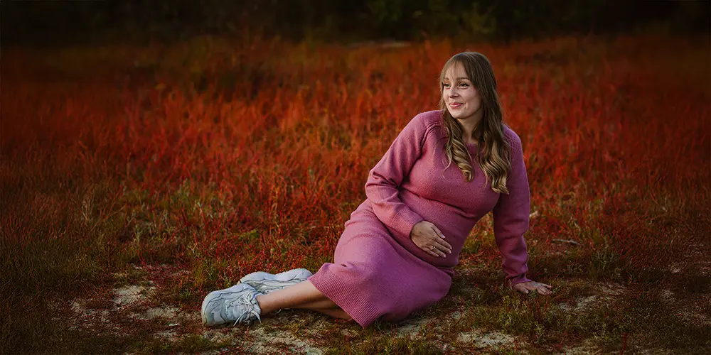 Zwangere vrouw vastgelegd in sfeervolle portretfotografie tijdens een natuurlijke zwangerschapsshoot op een locatie in de natuur