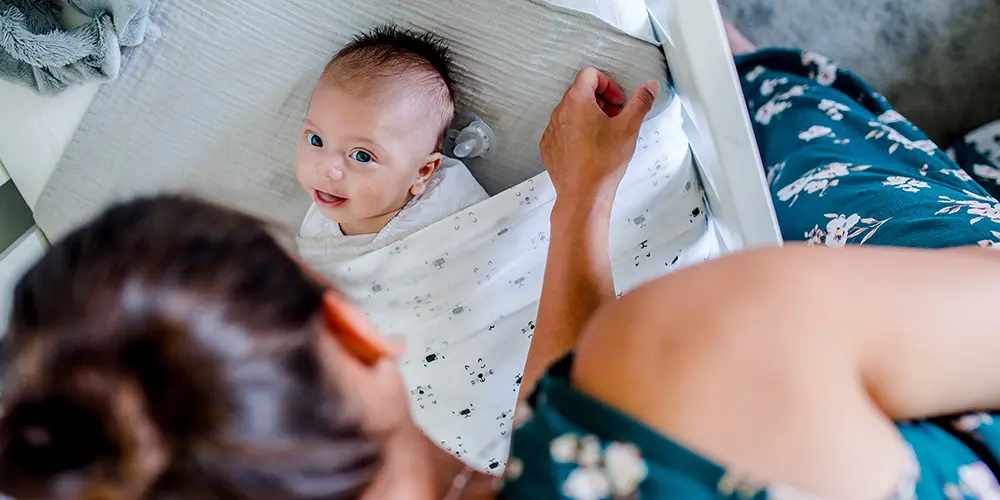 Een newborn baby wordt uit bedje gehaald tijdens een fotoshoot thuis